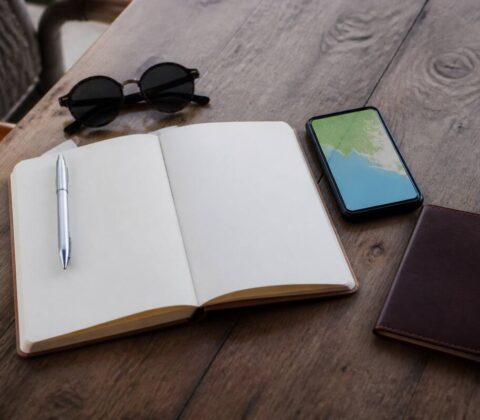 Reisplanning op tafel met notitieboek, smartphone en vakantiespullen