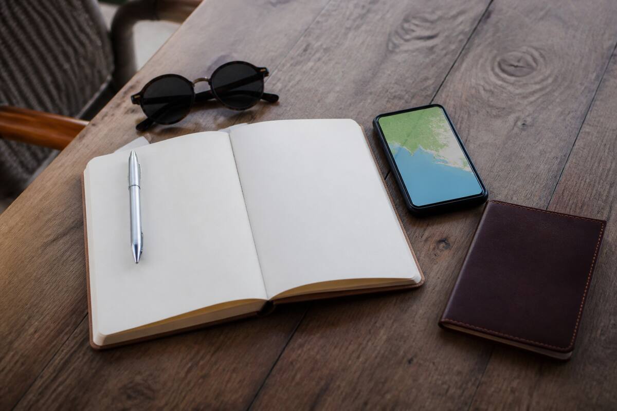 Reisplanning op tafel met notitieboek, smartphone en vakantiespullen