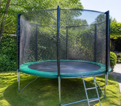 Trampoline met veiligheidsnet en randkussen in een tuin