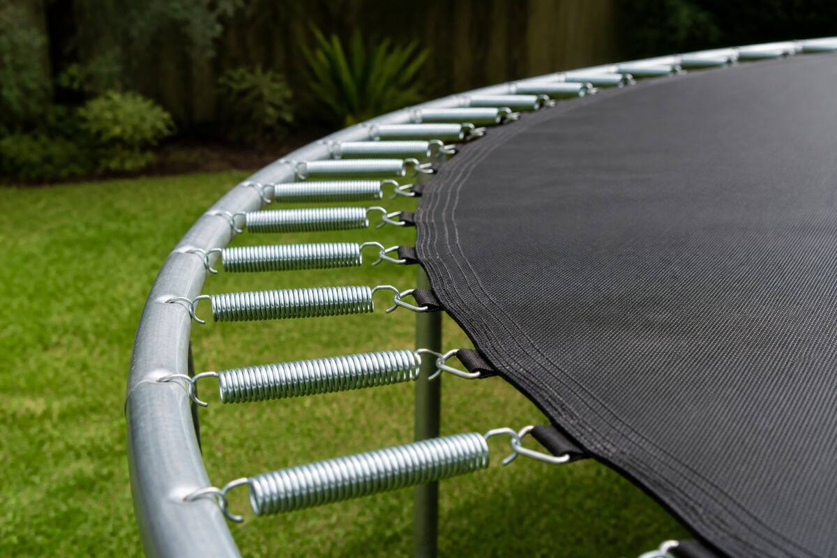 Trampoline in een tuin met zicht op springmat en frame tijdens het onderhoud
