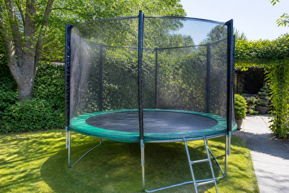 Trampoline met veiligheidsnet en randkussen in een tuin